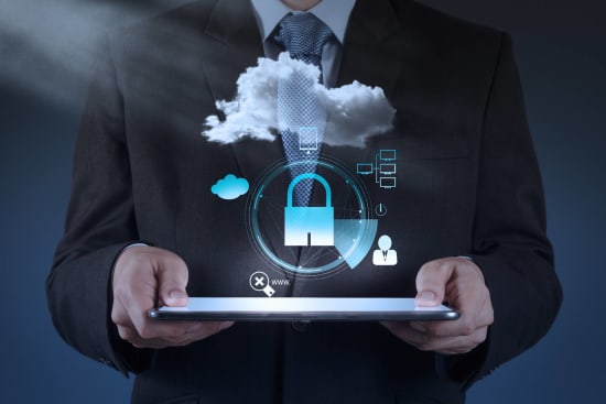 A man holds a tablet. Above the tablet floats a cloud and a lock and some other symbols, indicating cloud application security